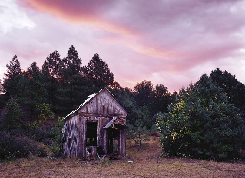 A soft pastel sunrise bathes the shambles of a cabin possibly built on Charles Taylor's original home site.