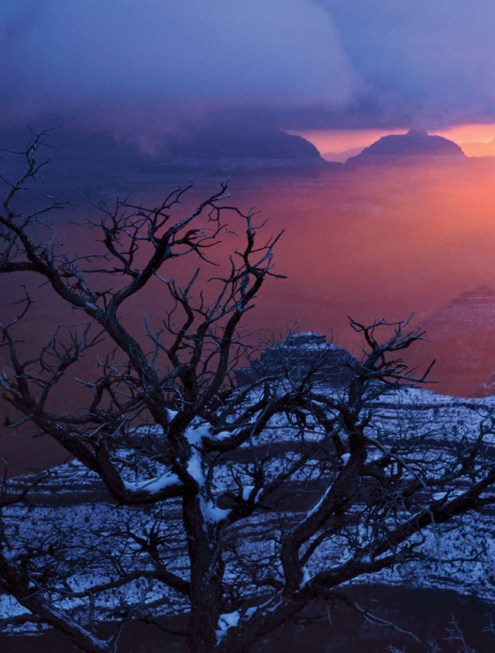 A blazing sunrise breaks through storm clouds after a fresh morning snowfall at Yavapai Point at the Grand Canyon.