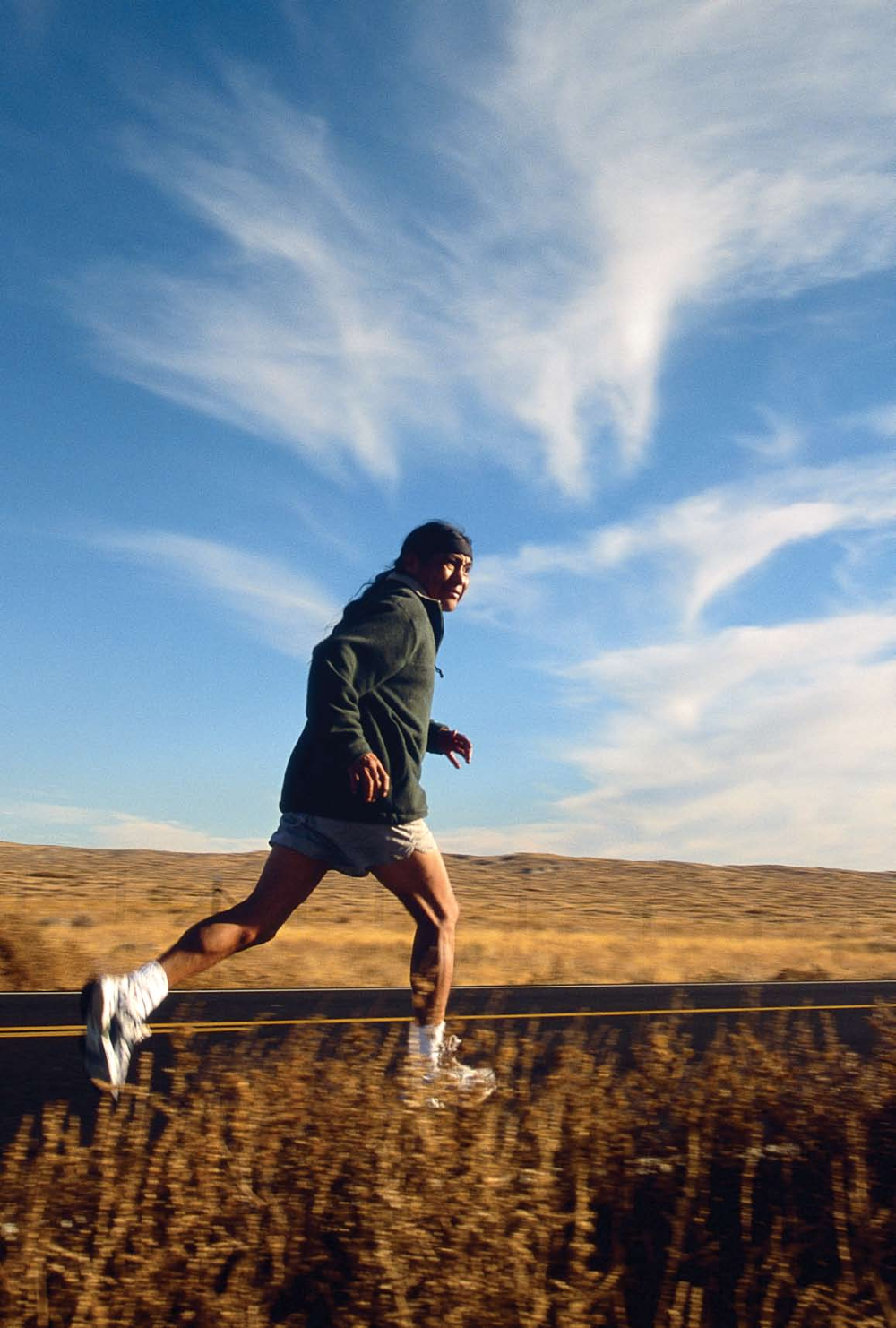 Dale Jackson runs along the road between the Hopi village of Moenkopi and Dilkon, on the Navajo Indian Reservation during a 100-mile training relay. Shadows for the red rock badlands on the Hopi Indian Reservation.