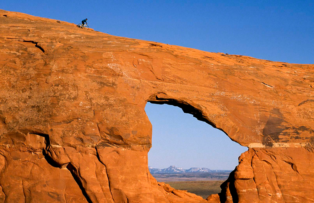 Brad Richman prepares to navigate his mountain bike over an opening in a Northern Arizona sandstone bench. Relatively mild temperatures and varied terrain make mountain biking a popular activity in the northern part of the state.