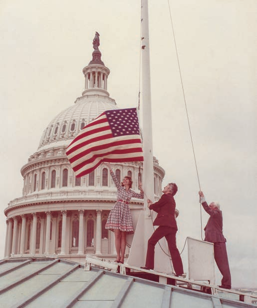 Associate Editor Wesley Holden (center) raises the bicentennial flag rug.