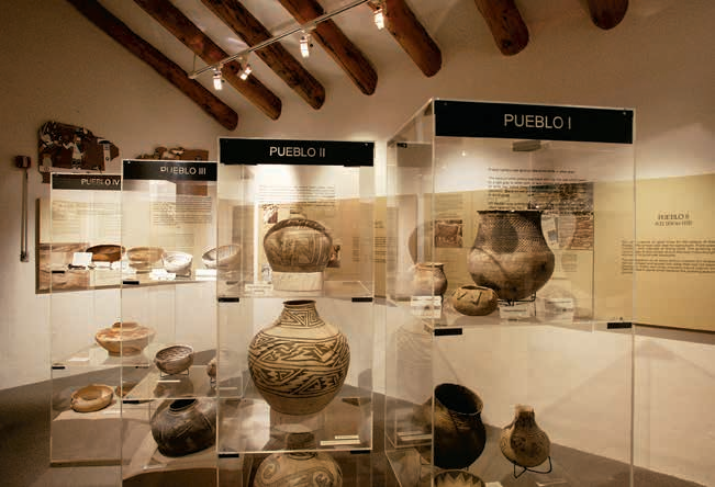 The creekside entrance of the museum peeks out between ponderosa pine trees, as seen from across Rio de Flag.