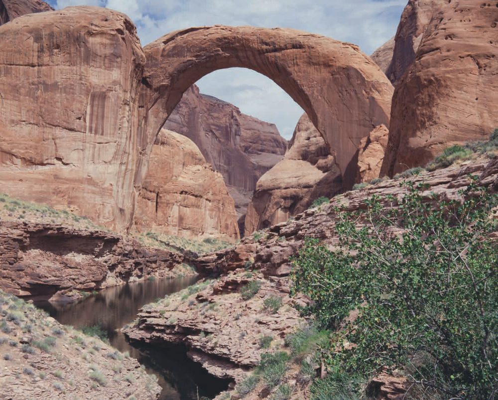 Rainbow Bridge arches over a sandstone landscape on the north side of Lake Powell. Despite often being described as an Arizona attraction, Rainbow Bridge is about 5 miles north of the state line, in Utah.