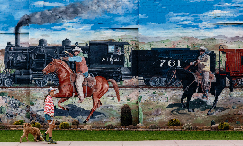 A pedestrian and her dog stroll past a massive mural in downtown Wickenburg. | Mark Lipczynski
