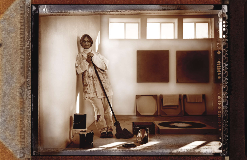 Here holding a cotton mop she transformed into a paintbrush, Hall often makes her own brushes from natural fibers, straw, grasses, mops and sponges. She also uses conventional paintbrushes.