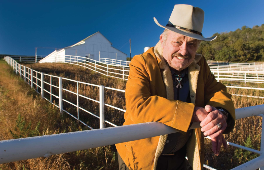 Bill Brooks, John Wayne's longtime friend and pilot, wears the Duke's jacket and cowboy hat outside the 26 Bar Ranch.