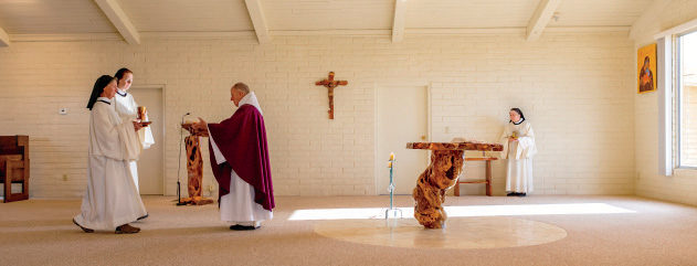 From left, Sister Victoria and Sister Pam bring Santa Rita Abbey's Holy Communion plate, which holds altar breads made at the abbey, to Father Thomas to celebrate the Eucharist. In the background, Sister Rita serves as the acolyte. Another nun, Sister Esther, crafted the abbey's altar from the trunk of a mesquite.