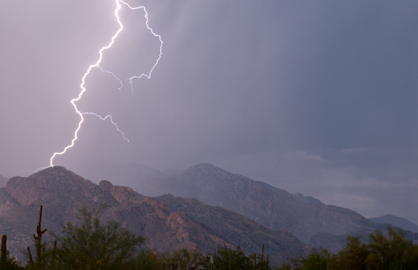 As rain shrouds the Santa Catalina Mountains, a bolt of lightning appears to strike one of their peaks.